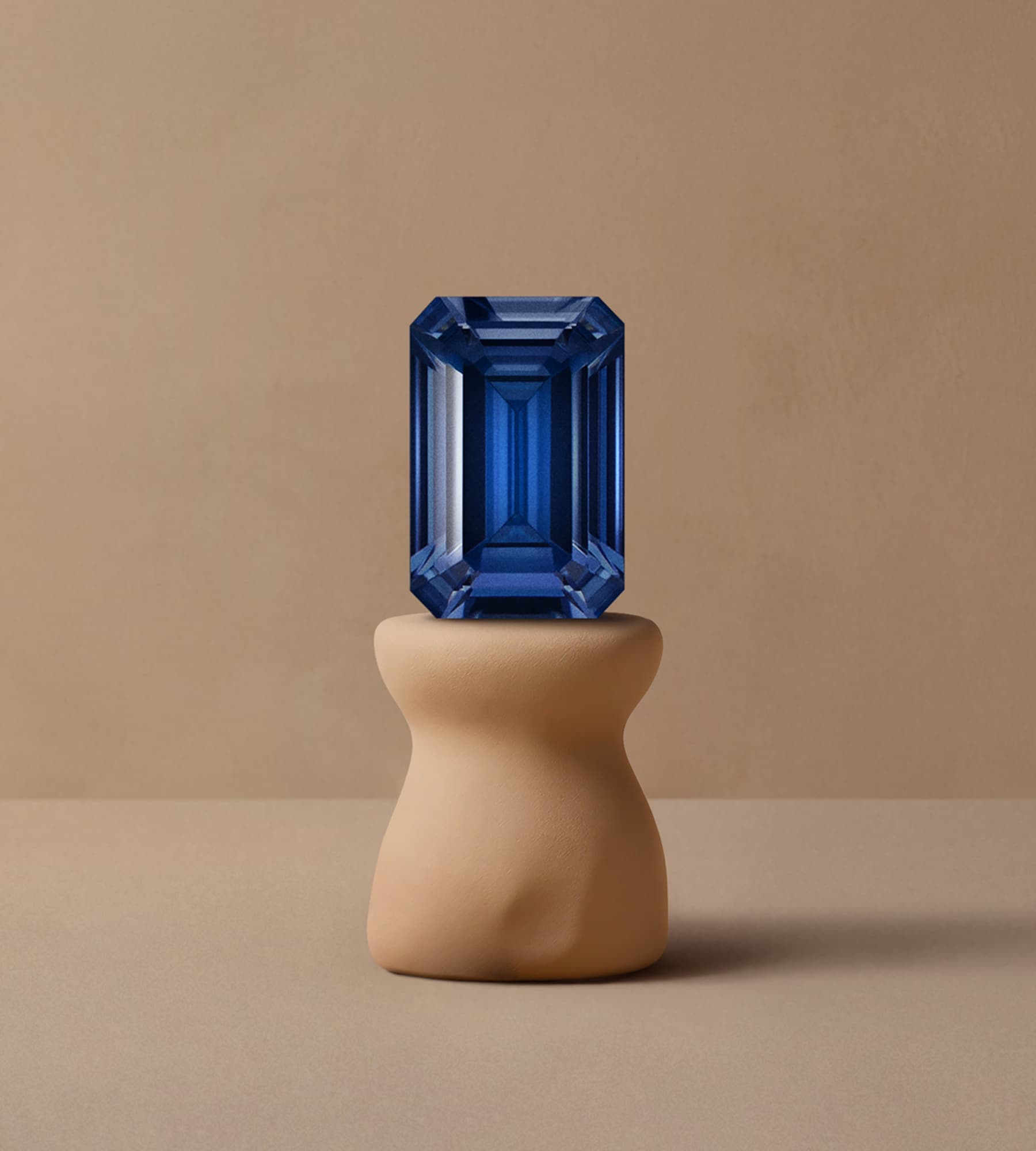 Saphir bleu taille émeraude posé sur podium céramique beige
